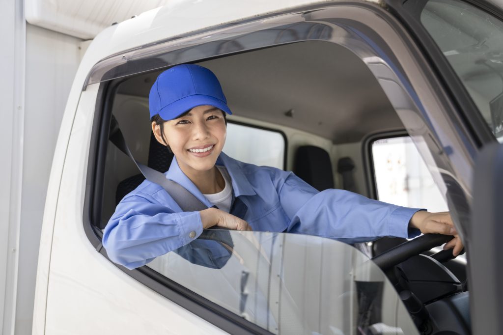 トラック運転席から微笑む女性ドライバー