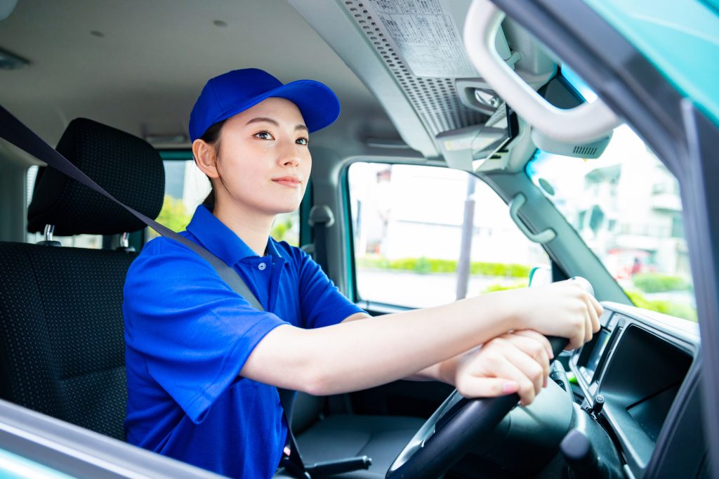 トラックを運転する青いポロシャツの女性